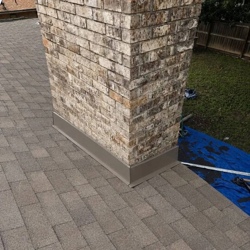 Brick chimney with metal flashing where it meets new shingles