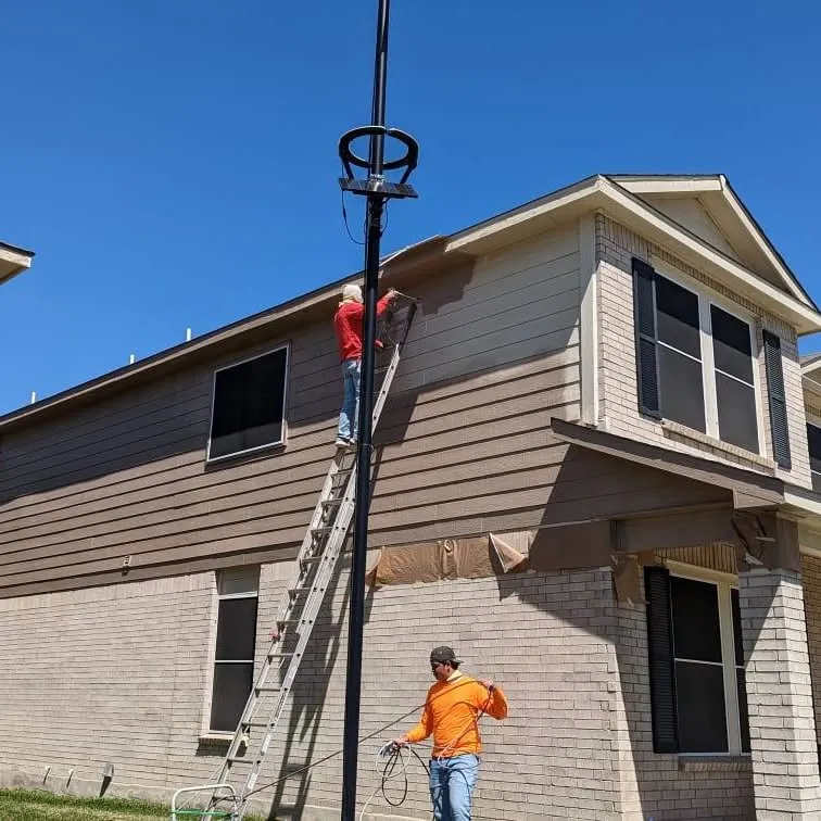 Painters on ladders working on the exterior of a two-story house