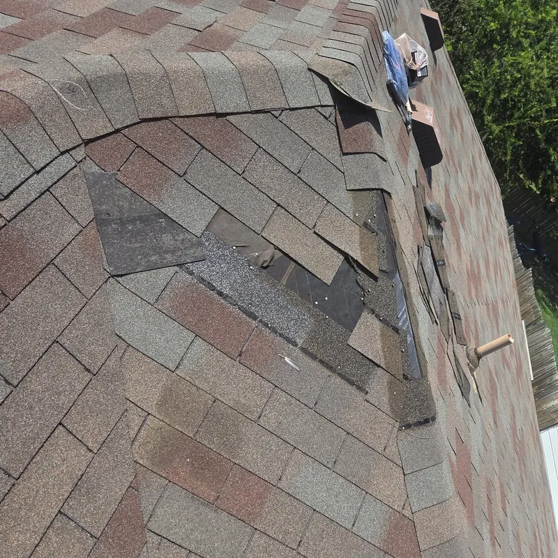 Shingle roof with torn and missing shingle tabs after a wind storm