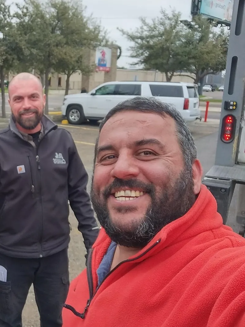 Richard Puigdomenech, owner of PCG Roofing, in a red jacket, with a crew member behind him